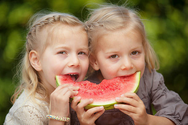 istock little twin girls eating melon 579137408