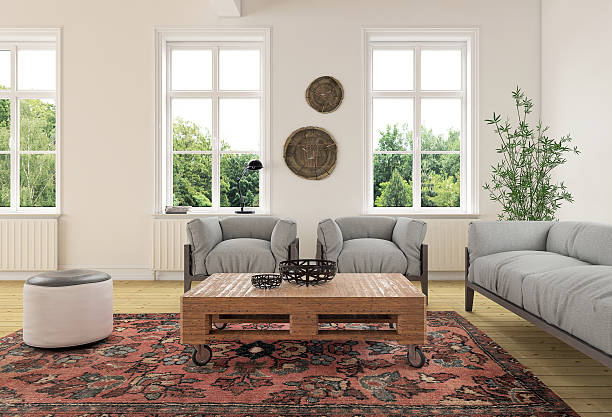 Modern classic living room interior View at eclectic living room interior showing a sofa and two armchairs and a cushion seat in a vintage modern colonial style. Large classic window design with tree in the background. Brightly lit daylight scene. Vintage ornate carpet with furniture made of wood. Horizontal composition. colonial style stock pictures, royalty-free photos & images