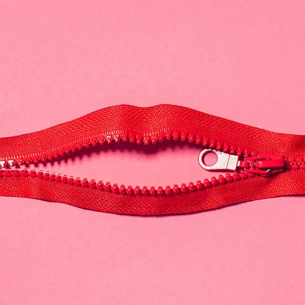 Red zipper in shape of lips on pink background