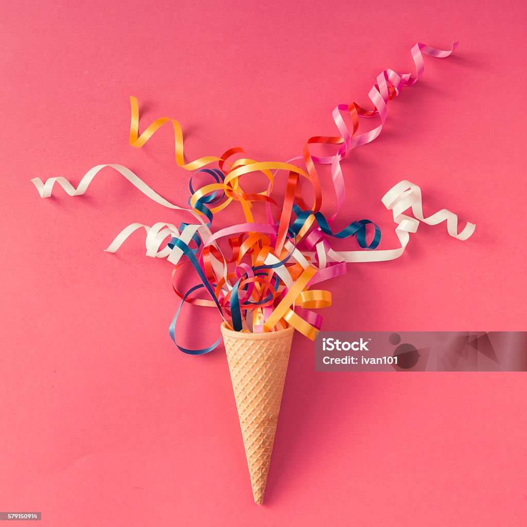 Ice cream cone with party streamers Ice cream cone with colorful party streamers on pink background. Flat lay Ice Cream Stock Photo