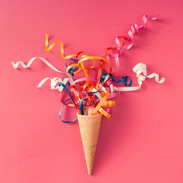 Ice cream cone with party streamers Ice cream cone with colorful party streamers on pink background. Flat lay knolling concept stock pictures, royalty-free photos & images