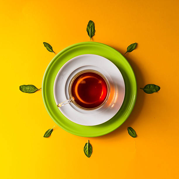 istock Tea in glass cup with green leaves  on orange background. 579152336
