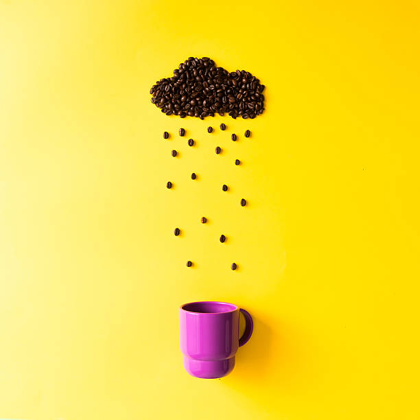 Coffee beans in shape of rainy cloud with cup. Coffee beans in shape of rainy cloud with purple cup on yellow background. Weather concept. rainy cafe stock pictures, royalty-free photos & images