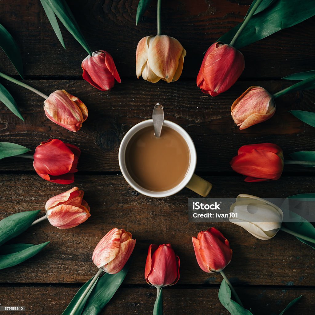 Coffee cup with creative arrangement of tulips  on wooden backgr Coffee cup with creative arrangement of tulips  on dark wooden background. Flat lay. Arrangement Stock Photo