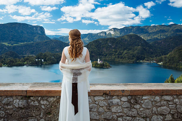 noiva em um castelo olhando para o lago bled, eslovênia - santa maria church - fotografias e filmes do acervo