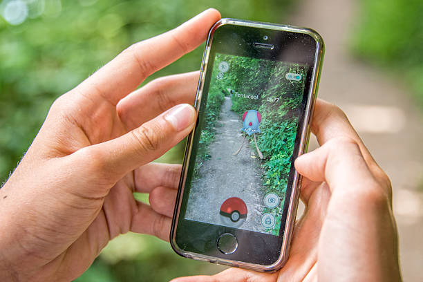 Meudon, France - July 24, 2016: Apple iPhone5s with Pokemon Go application, hands of a teenager playing in the forest of Meudon on the first day of the lanching of the game in France