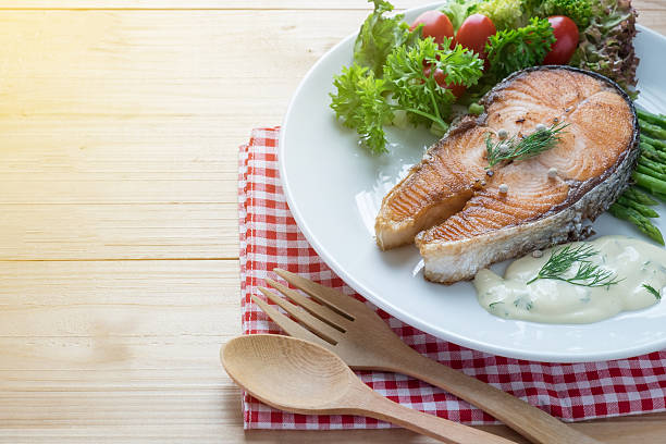 istock Fried salmon with vegetable on a round white plate 579218132
