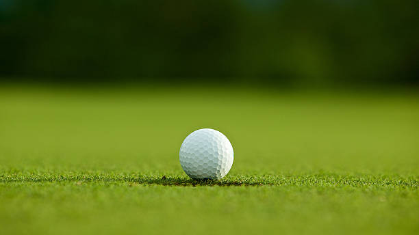 istock selective focus. white golf ball near hole on green grass 579218388