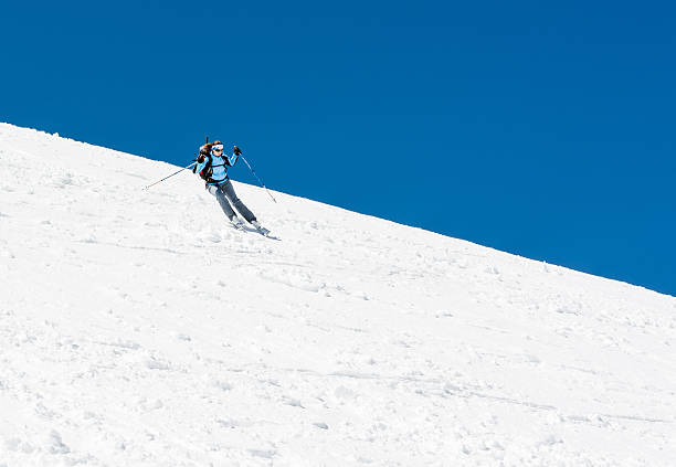 Female skier tackling a steep slope. stock photo