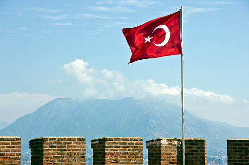 Antalya, Turkey - September 27, 2015: The Kızıl Kule (Red Tower) is a historical tower in the Turkish city of Alanya. The building is considered to be the symbol of the city, and is even used on the city's flag. Construction of the building began in the early reign of the Anatolian Seljuq Sultan Ala ad-Din Kay Qubadh I and was completed in 1226. The name derives from the more red color brick he used in its construction. The building itself is 33 m (108 ft) high and 12.5 m (41 ft) wide. It remains one of the finest examples of medieval military architecture, and is the best preserved Seljuk building in the city. The tower was depicted on the reverse of the Turkish 250,000 lira banknotes from 1992–2005.
