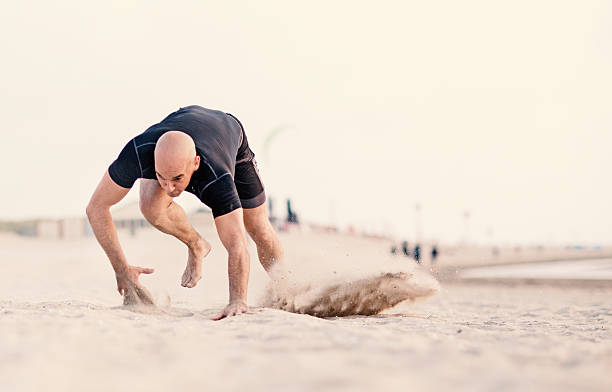 ハンサムな剃った運動男性は砂浜で働く - 這う　男性 ストックフォトと画像