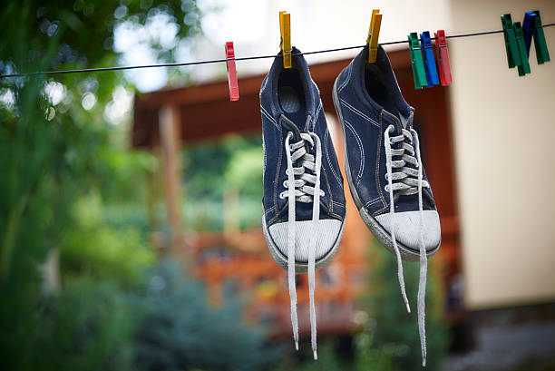 Le scarpe da ginnastica nere sono appese a una linea di abbigliamento - foto stock