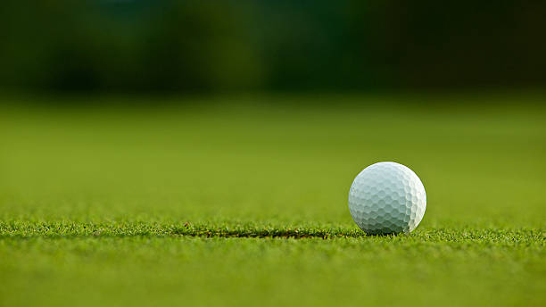 istock selective focus. white golf ball near hole on green grass 579227550