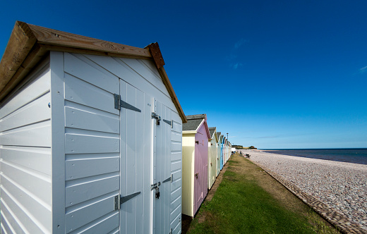 Beach Huts by the beach in Budleigh Salterton, a seaside town near Exmouth and Exeter in Devon, UK. Logos removed and people too small to be recongisable.