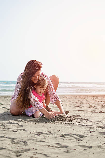 istock Mother and daughter playing in sand 579228072