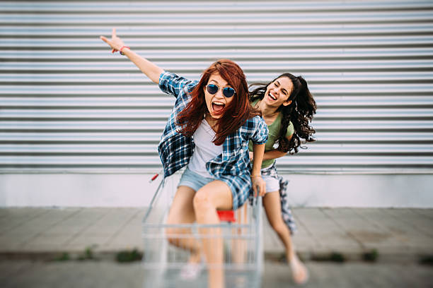 Two young girls having fun with a shopping cart.