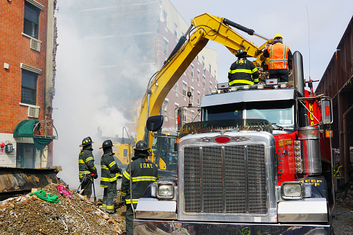 New York, NY, USA - March 13, 2014. Firefighters and construction vehicles removing debris the day after the 2014 East Harlem gas explosion.