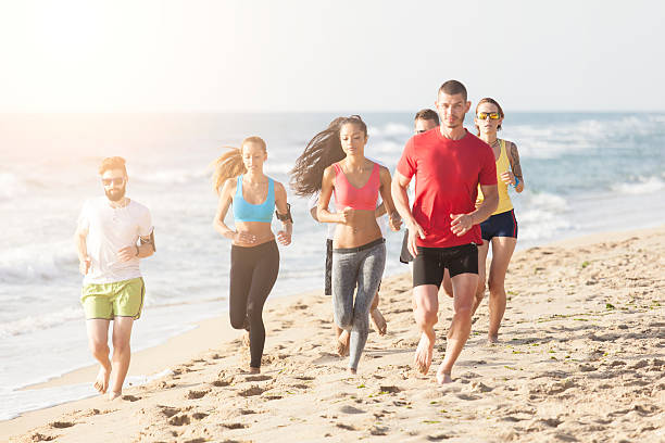 istock Group of young people running together on the beach 579241548