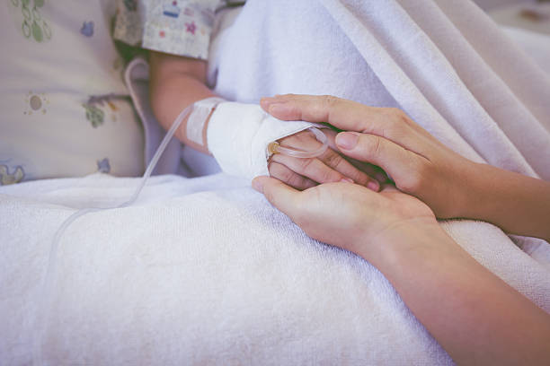 Close up hand of parent holding child's hand in hospital. stock photo