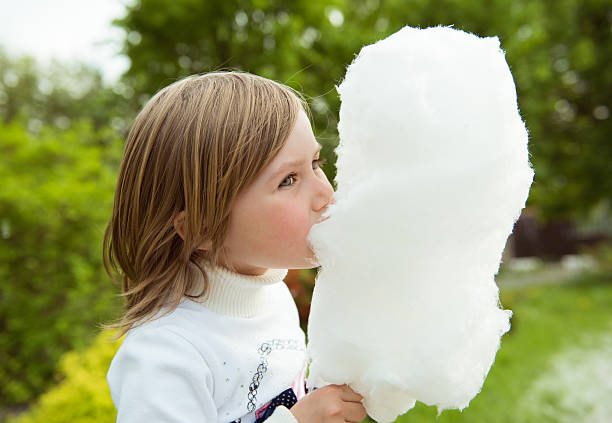 istock girl eating cotton candy 579246574