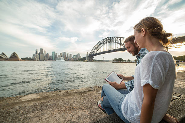 istock Couple consulting digital tablet, Sydney skyline on background 579248742