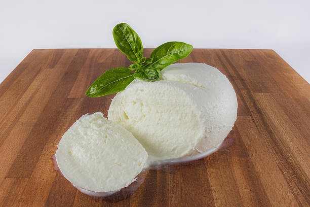 Mozzarella white mozzarella cheese with a basil leaf on a wooden cutting board buffalo iowa stock pictures, royalty-free photos & images