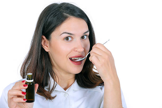 woman eating medicine on spoon