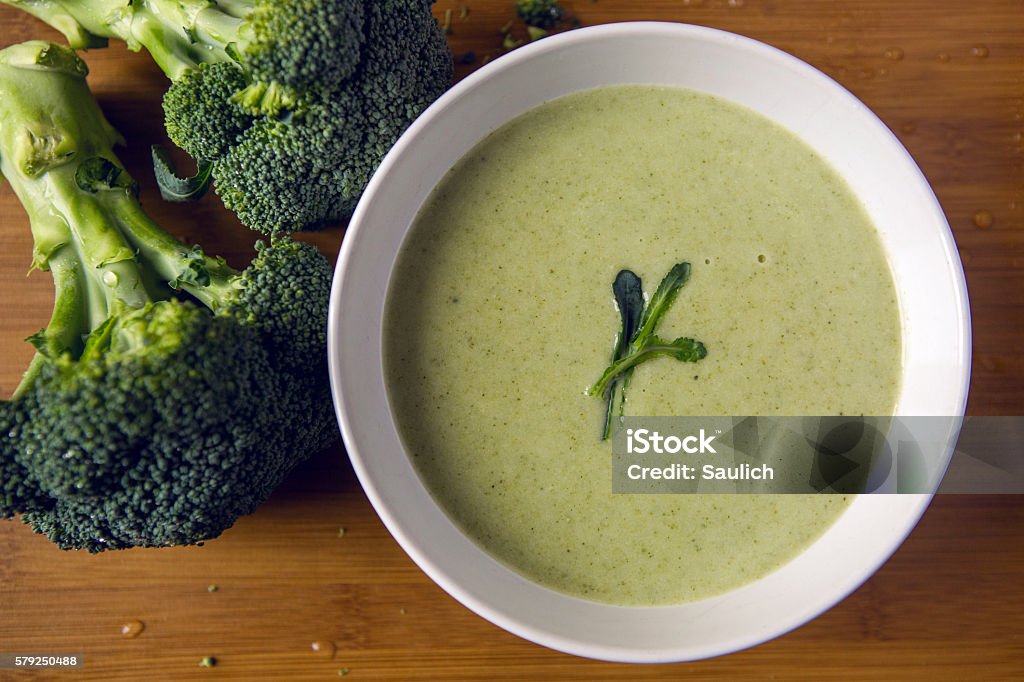 cream of broccoli soup cream of broccoli soup in a white bowl on a wooden table with slices of the stems Broccoli Stock Photo