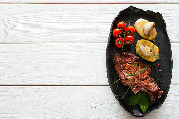 Grilled steak and potato, white wood, copyspace