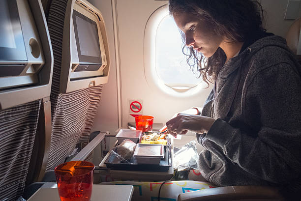 Woman eating lunch in airplane stock photo