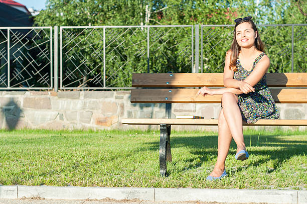 istock Girl smiling in park wearing sitting on bench 579263280