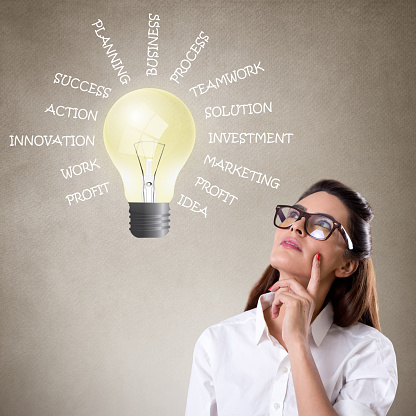 Businesswoman looking at glowing light bulb with solar panel. The glowing light bulb is a symbol of success.