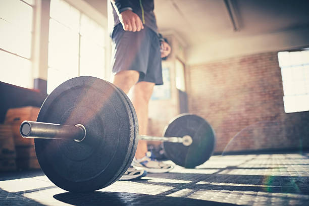 istock Low angle view of man standing over barbell in gym 579265542
