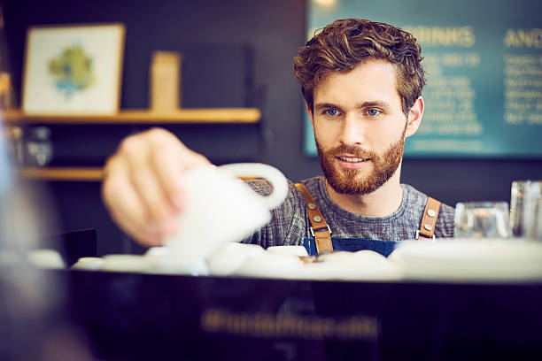 Barista looking at coffee cup in cafe