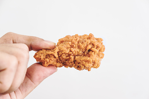Close-up hand holding fried chicken, on white background