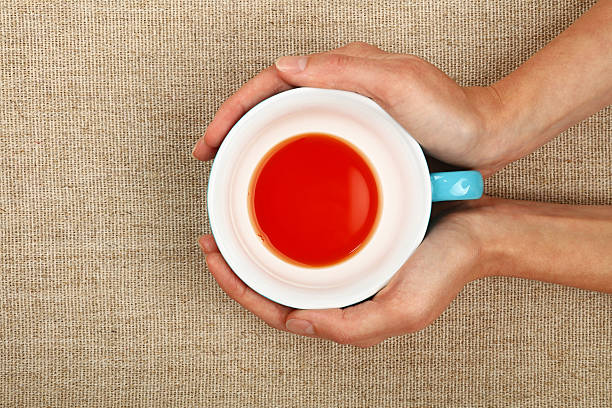 istock Two woman hands holding cup of black red tea 579401108
