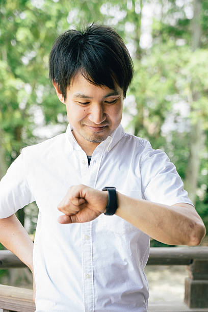 istock Japanese cheerful man using a smart watch outdoors 579404252
