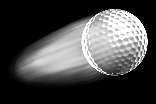 A flying golf ball isolated on black background.