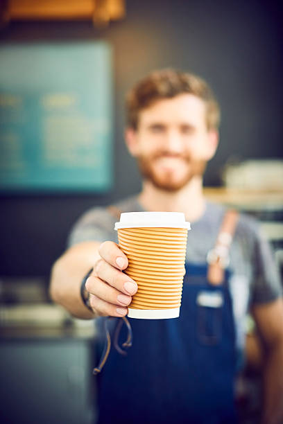 istock Male barista offering coffee in disposable cup 579407120