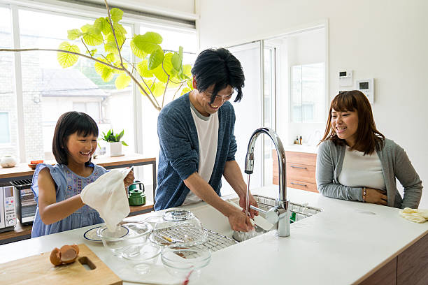 istock Father and daughter wash dishes while mother takes a break 579409028
