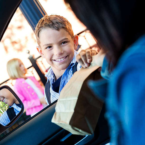 istock Mom hands elementary son his lunch in carpool line 579409216