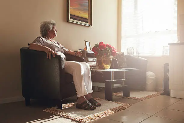 Photo of Senior woman sitting alone on a chair at home