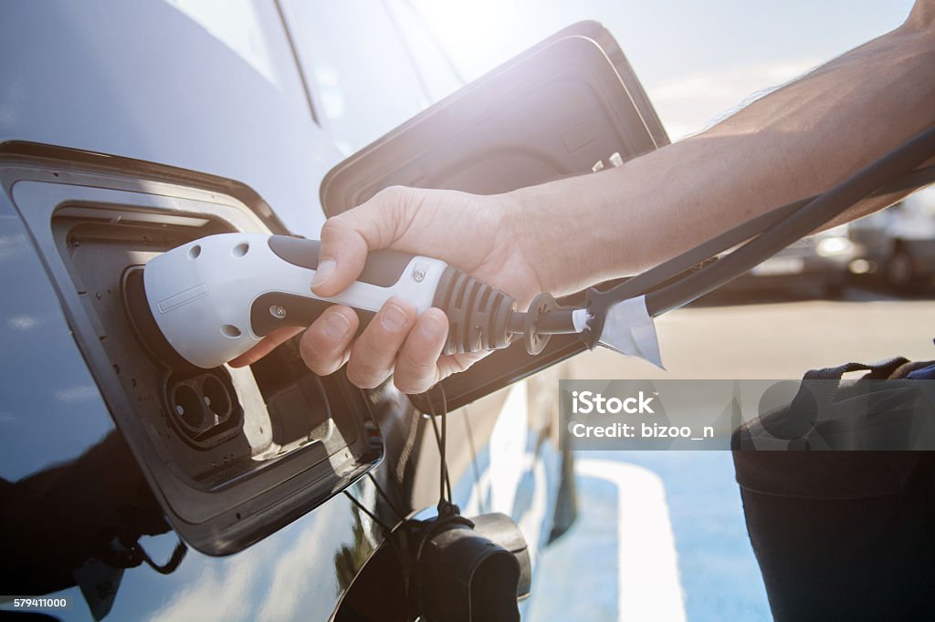 Electric car charging Color image of a man's hand preparing to charge an electric car. Electric Vehicle Charging Station Stock Photo