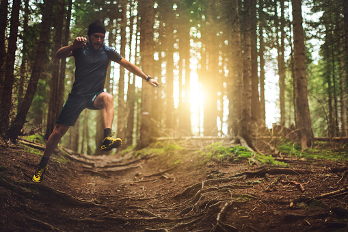 A man exercise trail running in a green forest