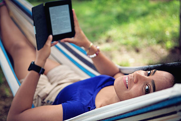 istock Beautiful girl is reading e-book in the hammock 579411874
