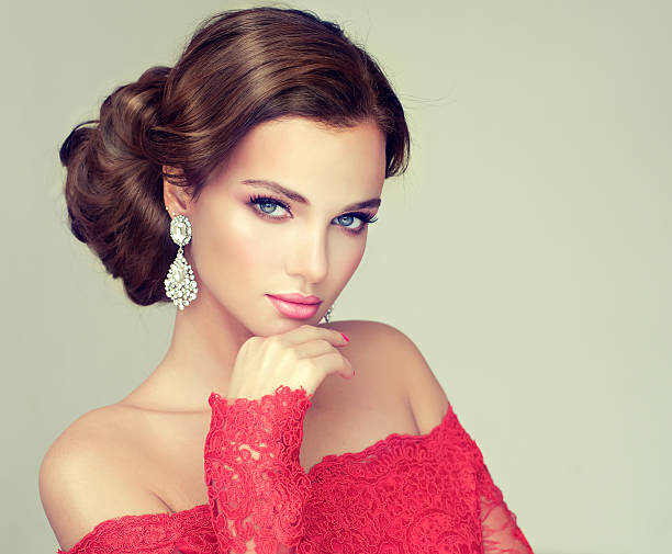 Young, gorgeous model dressed in a wedding and evening style. Young, gorgeous model put on in a delicate make up, and dressed in a red gown. Misty, romantic look. Wedding and evening style. hairstyle bride jewelry women stock pictures, royalty-free photos & images