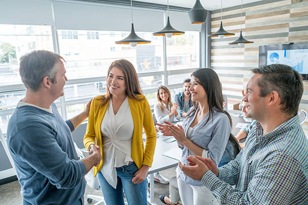 Business woman getting a promotion Business woman getting a promotion at the office and coworkers congratulating her ladder of success stock pictures, royalty-free photos & images