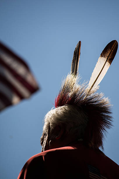 Kiowa elder and American flag, at the Kiowa Blackleggings Pow-wow. Anadarko, Oklahoma, U.S.A.  - October 11, 2015: Kiowa elder and American flag, at the Kiowa Blackleggings Pow-wow. kiowa stock pictures, royalty-free photos & images