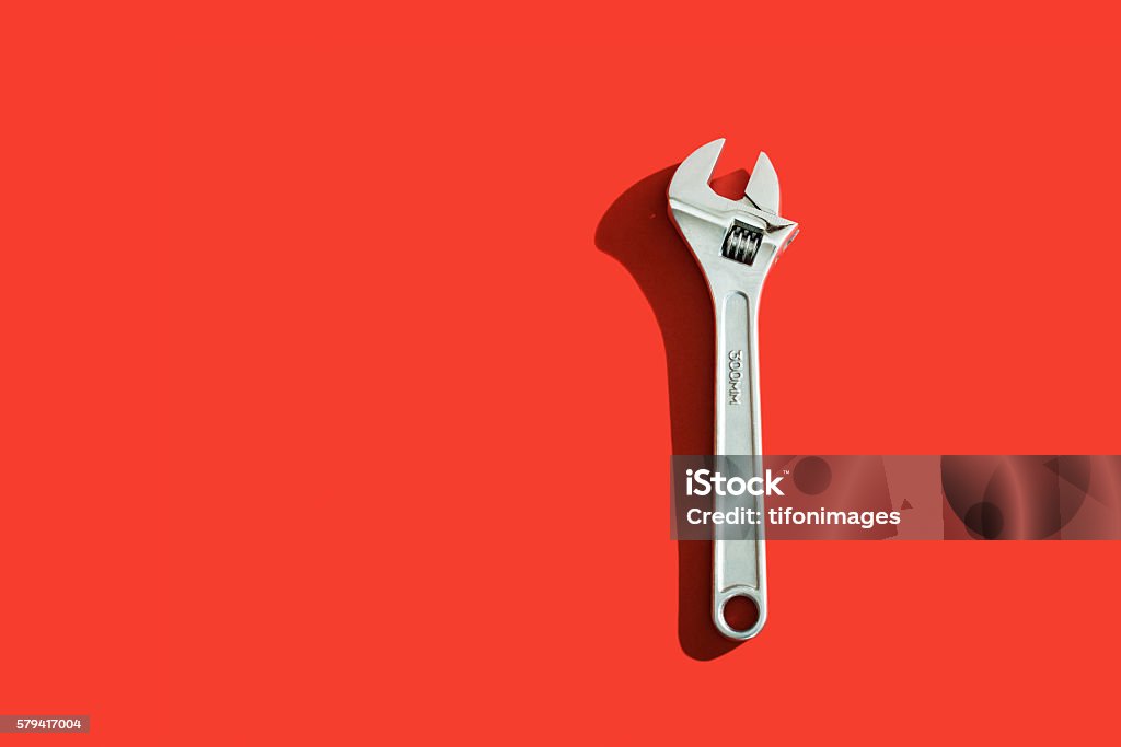 Silver Wrench Wrench with shadow over a red background Colored Background Stock Photo
