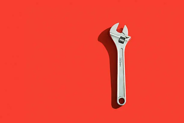 Wrench with shadow over a red background